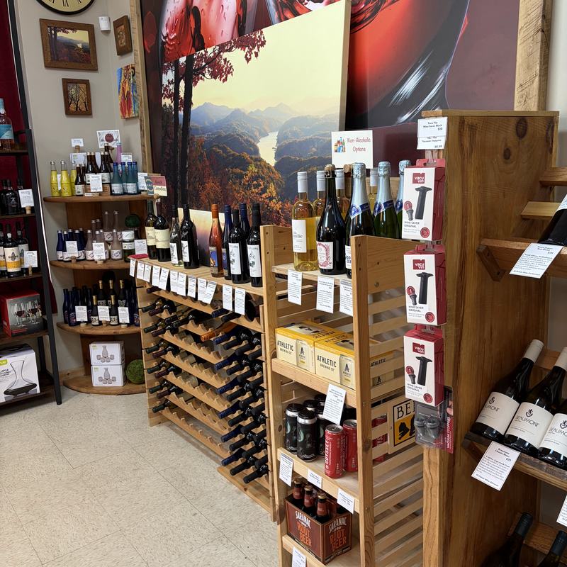 An aisle of wine racks and crate shelving beneath a large framed photograph of wine being poured