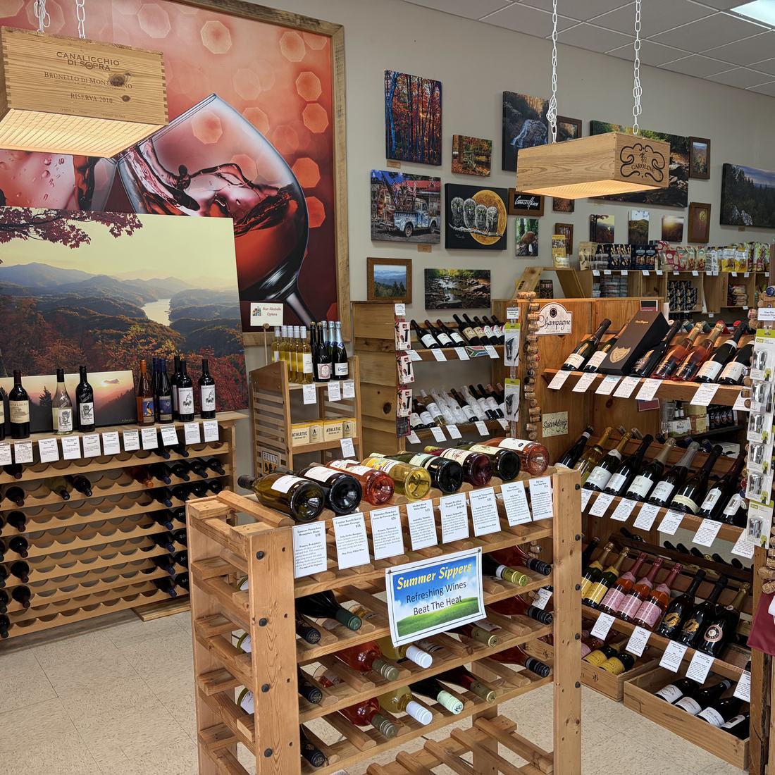 Inside Bryson City Wine Market, with wooden wine racks, a Summer Sippers display and local artwork covering the back wall