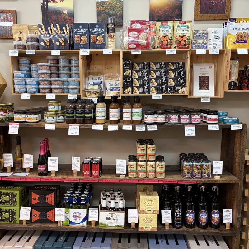 Shelves of gourmet pantry goods, jars, tins and packaged snacks alongside bottles of oil and vinegar