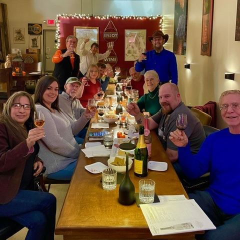 A full table of guests raising their glasses together at a tasting in the back room